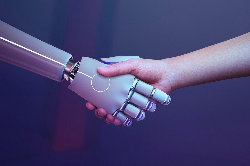 a robot hand and a human hand engaging in a handshake