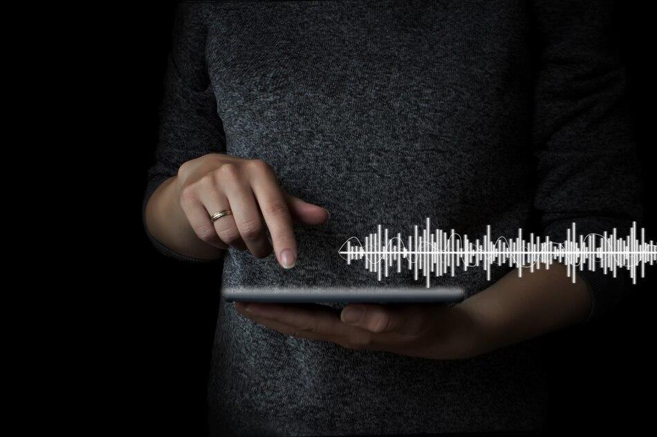 a person using a tablet with a digital sound wave visualization overlay, representing AI text-to-speech technology in use