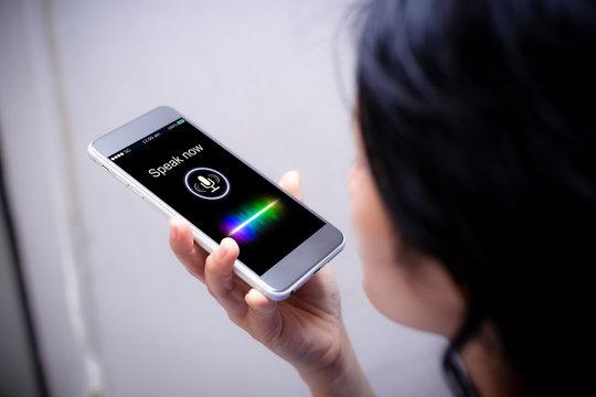 person holding a smartphone with a voice recognition interface