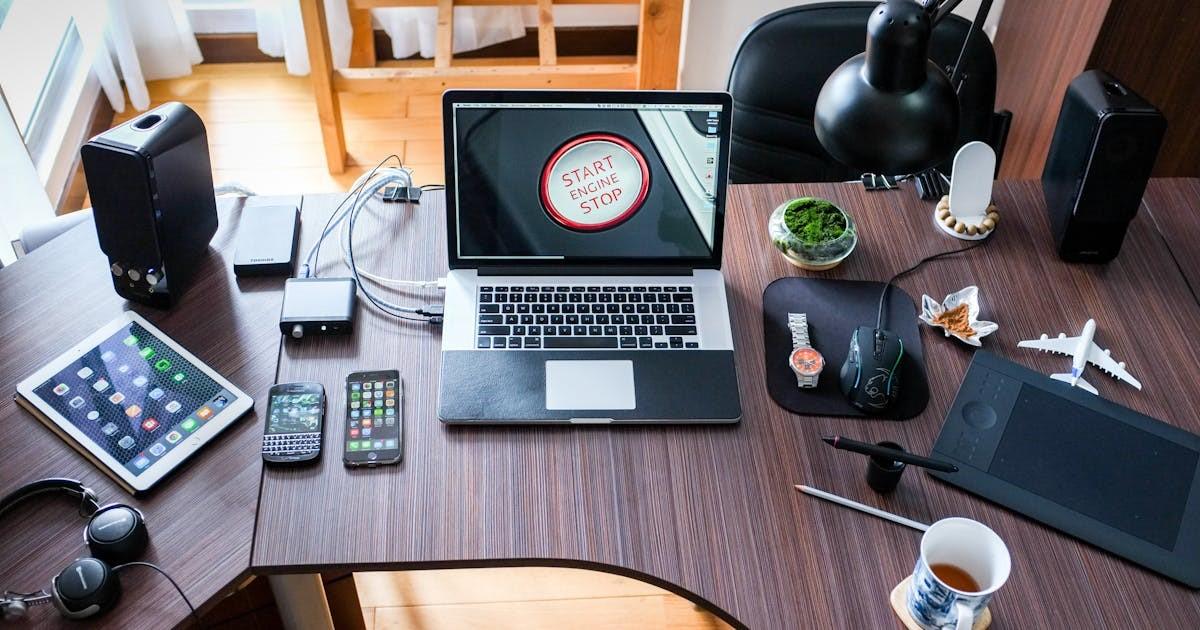 modern workstation with laptop, tablet, smartphones, and various tech gadgets on a desk