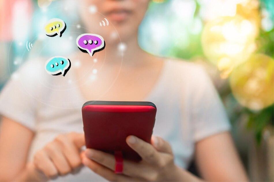 person holding a smartphone with floating chat bubble icons indicating digital messaging