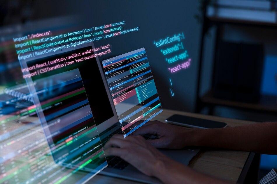 a person coding on a laptop with an overlay of code graphics and syntax from a programming environment