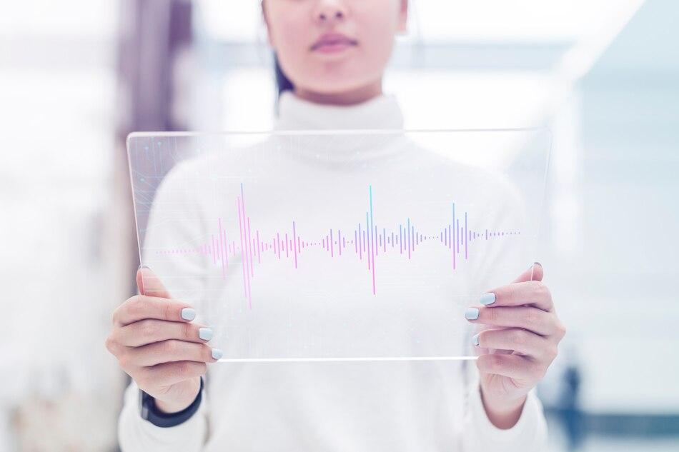 a woman holding a transparent display with a sound wave pattern on it